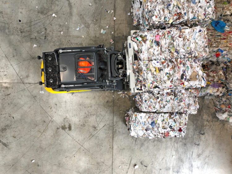 Photo illustrant un chariot élévateur manipulant des balles de déchets recyclables dans un centre de tri.